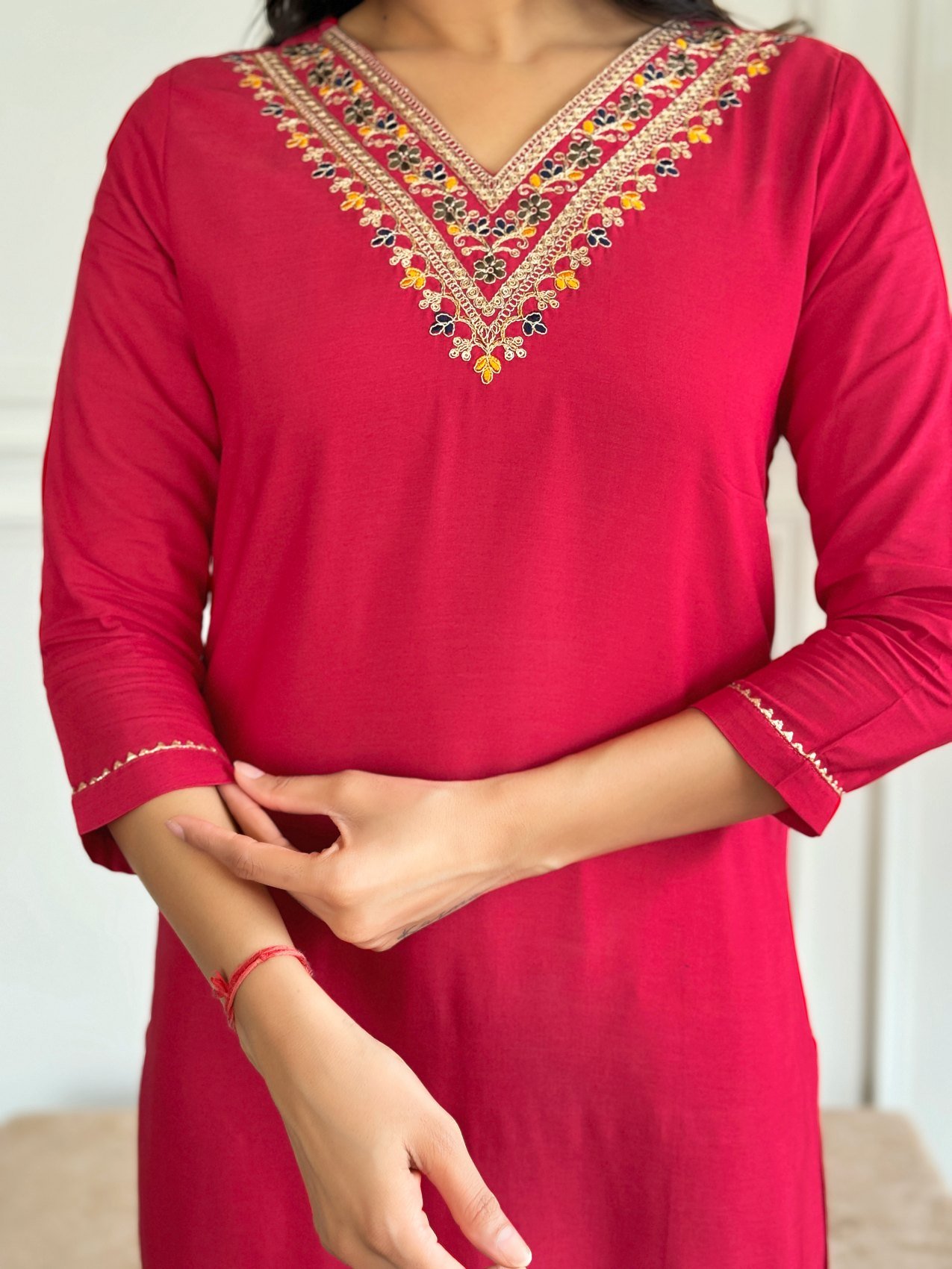 Close-up of the multicoloured embroidery at the V-neckline of the red kurta