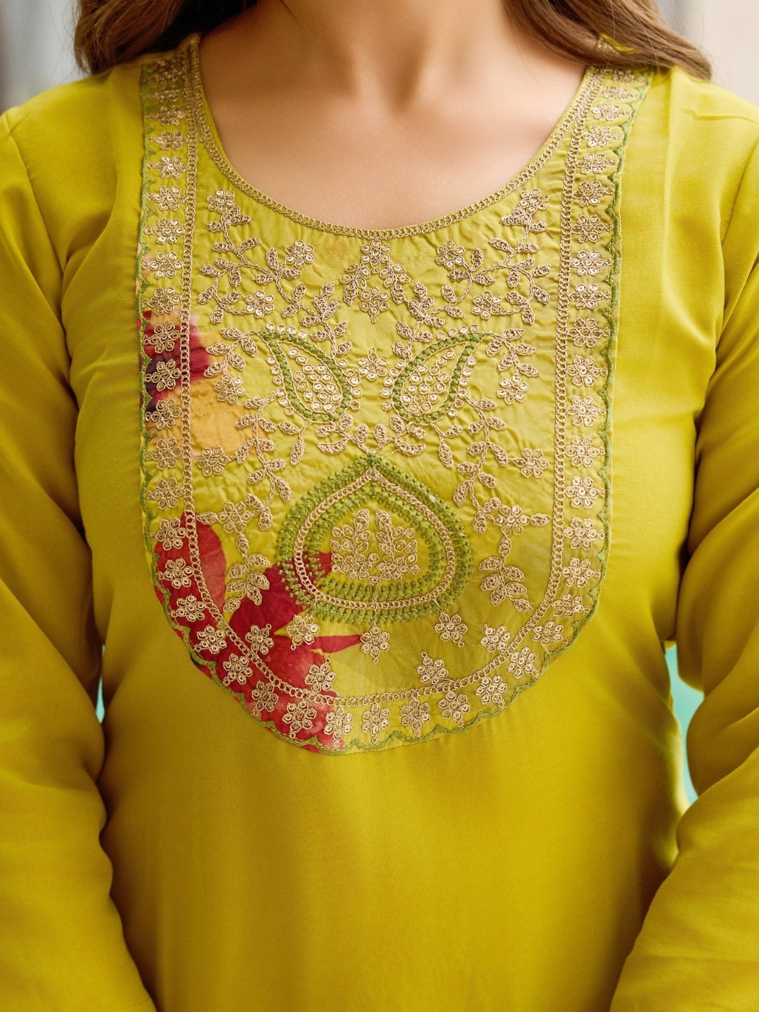Close-up of the embroidered yoke panel in gold and cream thread with coral floral accents