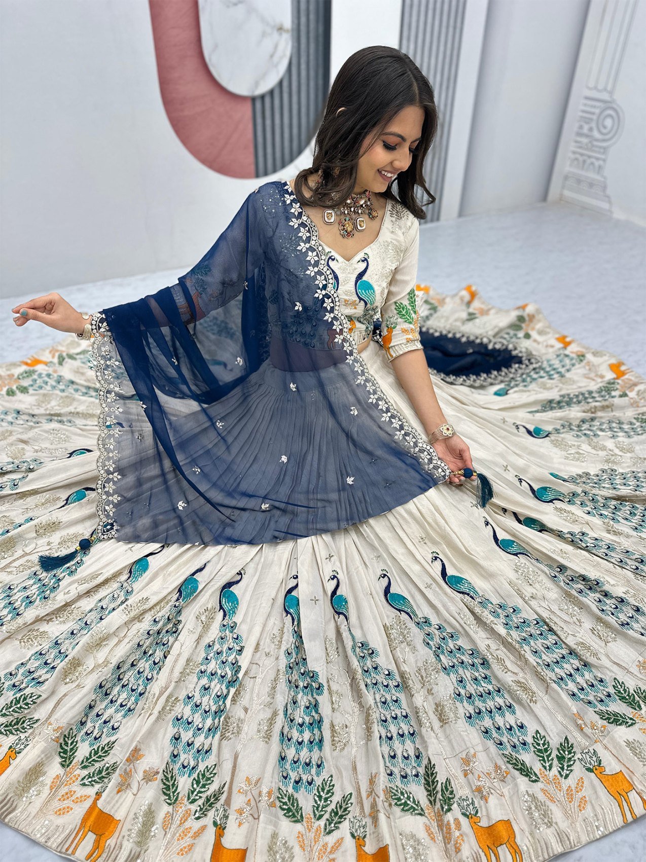 Close-up of the embroidered deer and peacock zari motifs on the ivory lehenga
