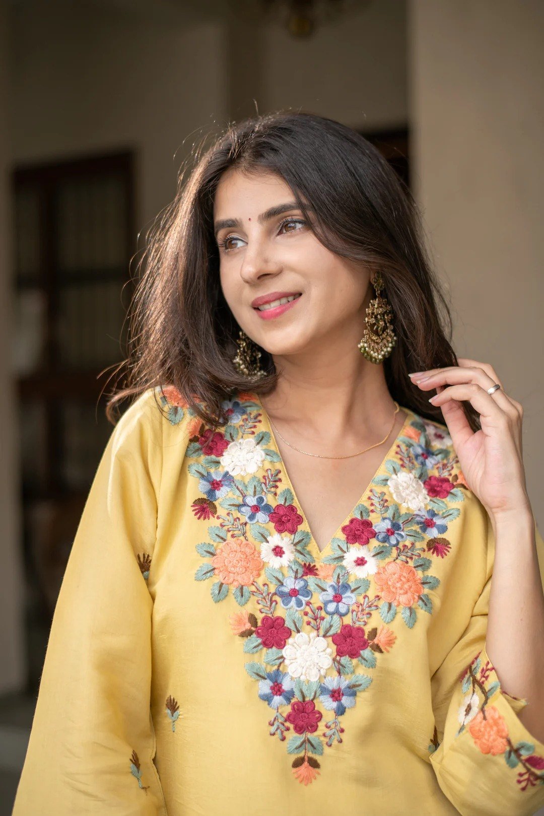 Close-up of the multicoloured floral embroidery at the V-neckline of the yellow kurti