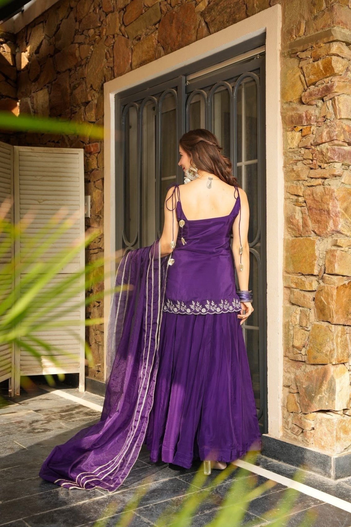 Back view of the purple top with fine shoulder straps and flared palazzo