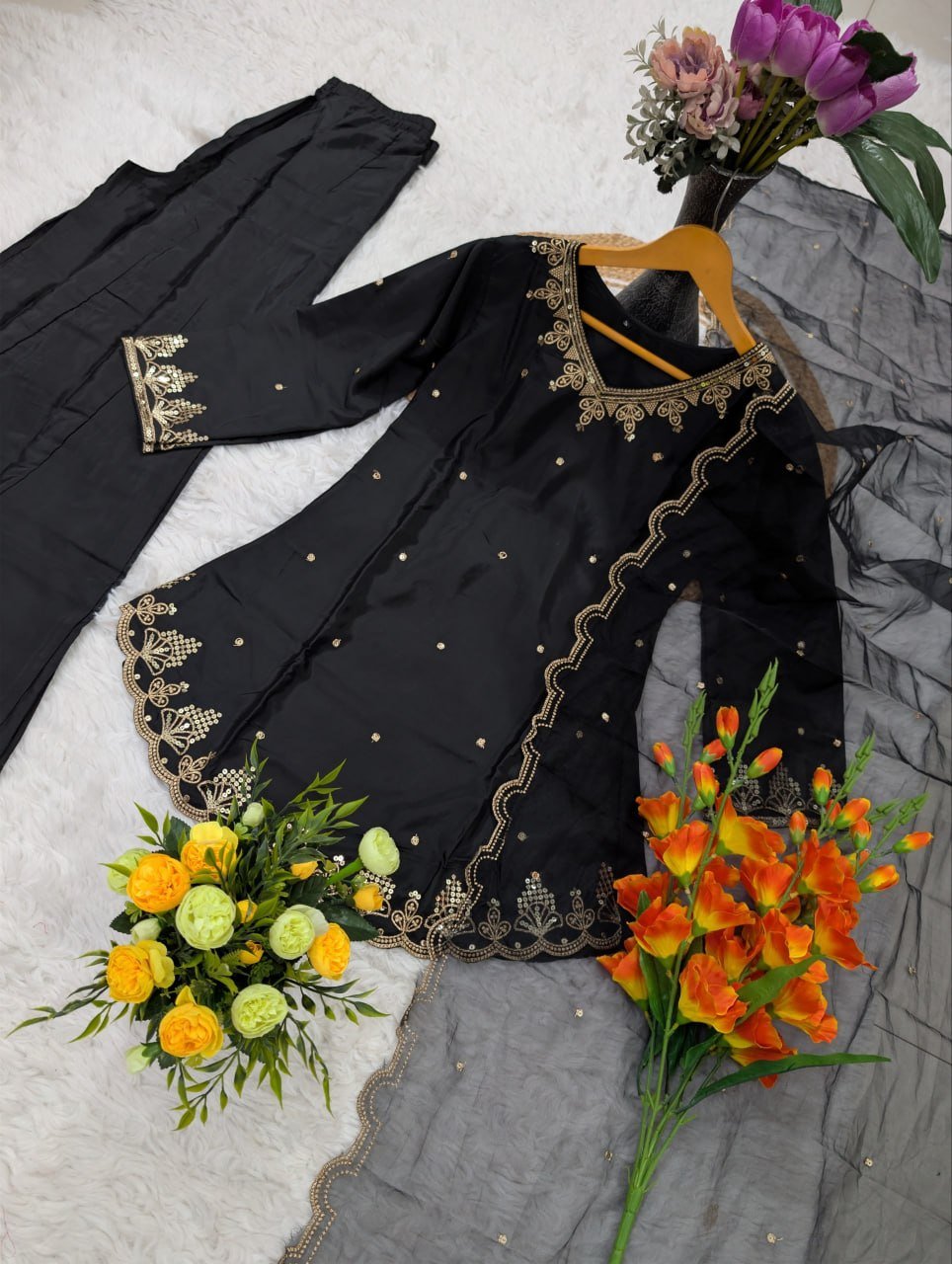 Flat lay of black embroidered kurta with scalloped hem, pant and organza dupatta